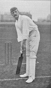 Black and white photograph showing John Auger Dixon playing Cricket. He is shown at bat, wearing a white shirt, white trousers and shin protection and a cap.